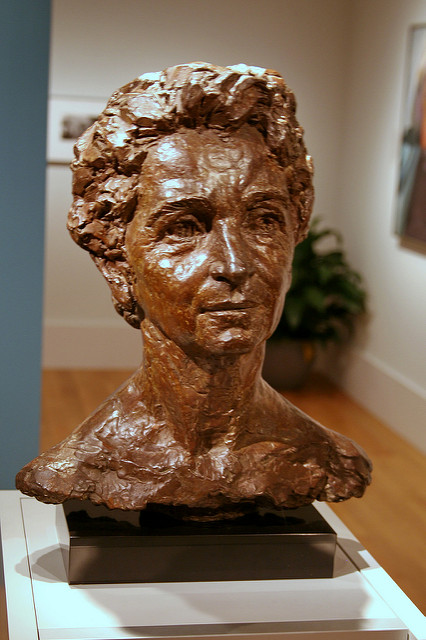 A bronze bust of Margaret Sanger under museum lighting.
